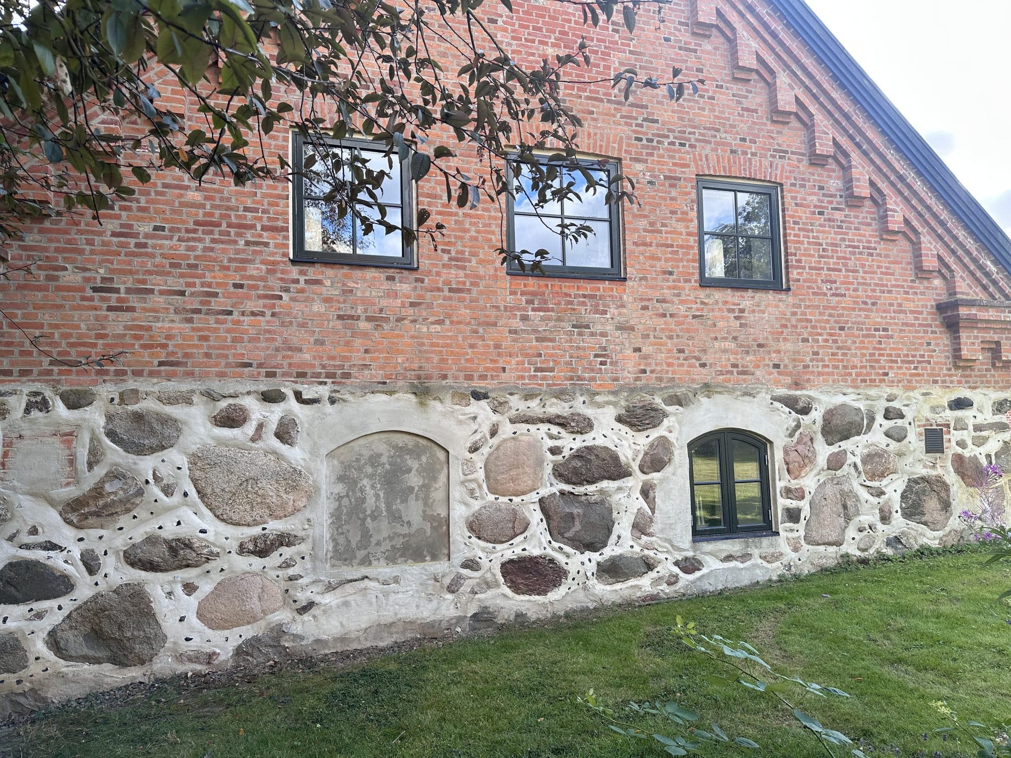 Byggnadens långsida i rött tegel med vitkalkad sockel av skånsk natursten